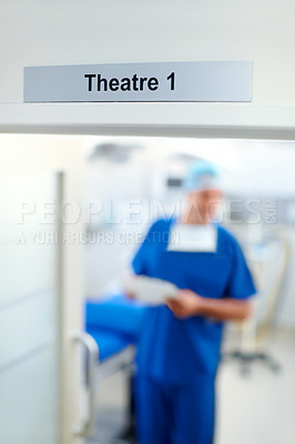 Buy stock photo Blurred image of a doctor wearing scrubs under a focused sign reading 