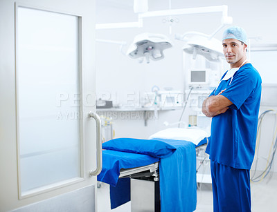 Buy stock photo A handsome male doctor standing next to an operating table
