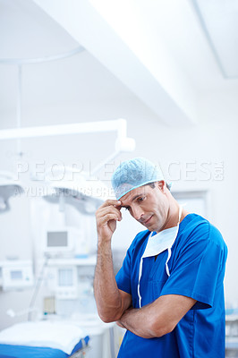 Buy stock photo A doctor rubbing his eyebrow looking somewhat anxious