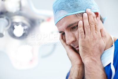 Buy stock photo Close-up a doctor looking somewhat distraught holding his head in his hands