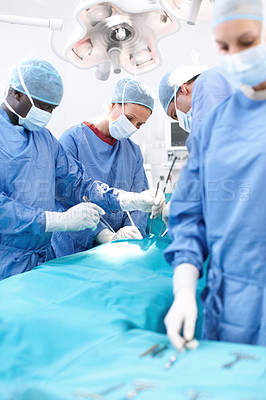 Buy stock photo Group of surgeons looking at a patient on an operating table during an operation