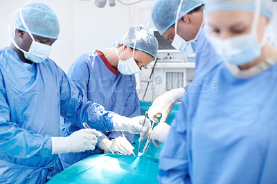 Buy stock photo Group of surgeons working on a patient lying down on an operating table during an operation