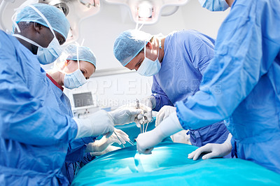 Buy stock photo Profile view of surgeons working together wearing scrubs in an operating room