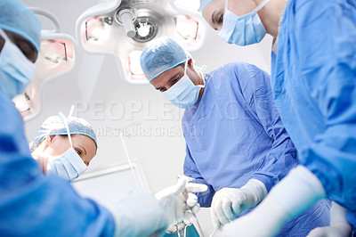 Buy stock photo Low view of medical doctors performing surgery in an operating theatre