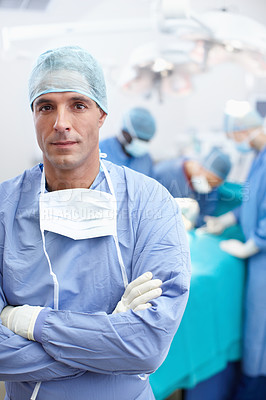 Buy stock photo Portrait of a serious surgical doctor standing with his arms crossed during a surgery