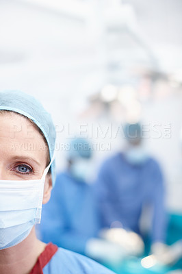 Buy stock photo Cropped closeup of a mature female surgeon wearing hospital scrubs and a protective face mask - Copyspace
