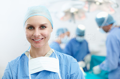 Buy stock photo Happy young female surgeon smiling with a group of surgeons in the background - Copyspace