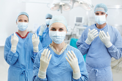 Buy stock photo Portrait of four surgeons holding up their hands wearing protective white gloves and face masks