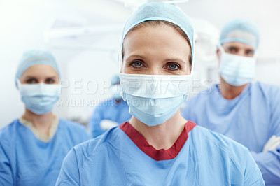 Buy stock photo Closeup portrait of a mature and experienced female surgeon with her medical staff behind her