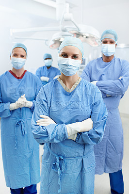 Buy stock photo Portrait of professional surgeons with face masks and hospital scrubs standing in an operating theatre together