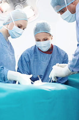Buy stock photo Female and male surgeons using medical forceps and scissors to operate on a patient in a surgery