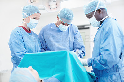 Buy stock photo Diverse group of medical surgeons operating on a patient in an operating theatre