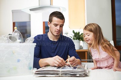 Buy stock photo Man, child and paper in home for recycling, environment care and teach social responsibility. Father, young girl and newspaper in living room for go green, eco drive and kid learning waste reduction