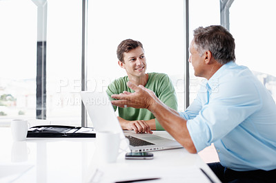 Buy stock photo A mature executive looking over some work on a laptop with a younger colleague