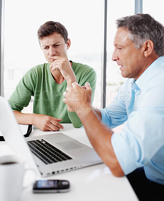 Buy stock photo A mature executive looking over some work on a laptop with a younger colleague