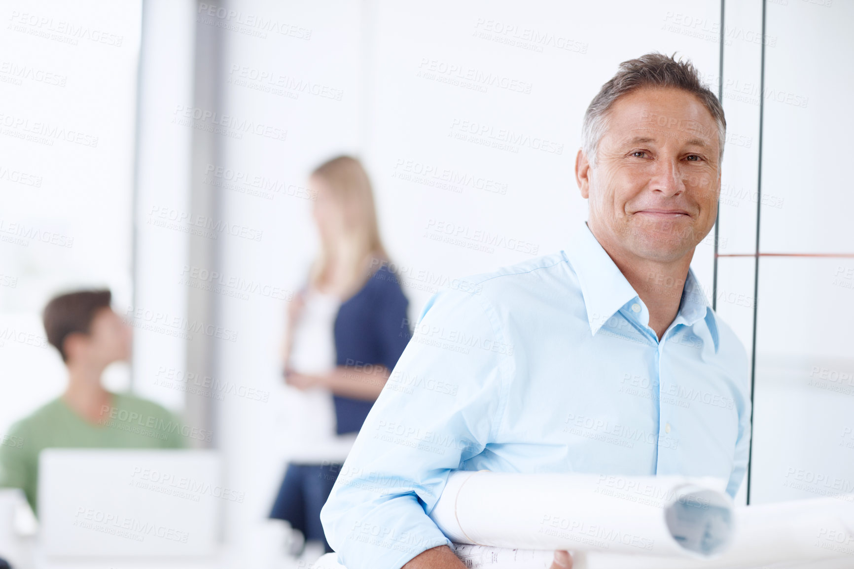 Buy stock photo A mature architect leaning against the door with his colleagues in the background
