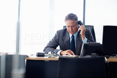 Buy stock photo A senior businessman taking a call at his desk
