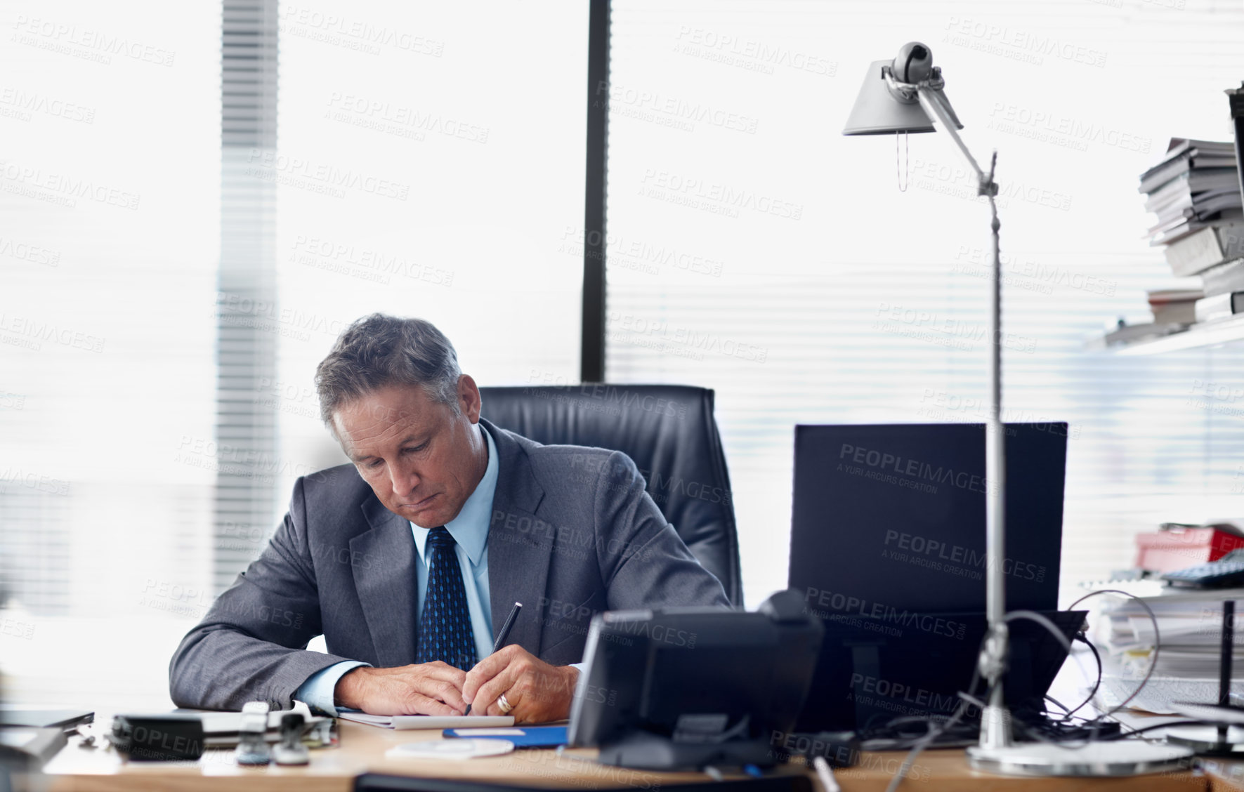 Buy stock photo A senior businessman working hard at his desk