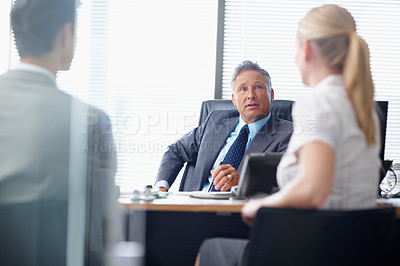 Buy stock photo A respected business manager holding a meeting with two younger colleagues in his office