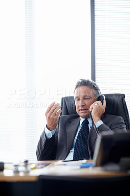 Buy stock photo A senior businessman taking a call at his desk