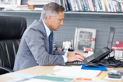 Buy stock photo A senior businessman working hard on a laptop at his desk