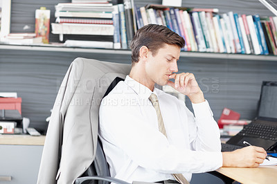 Buy stock photo A young executive ponders a business brief at his desk