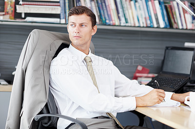 Buy stock photo A young executive gathering his thoughts at his desk