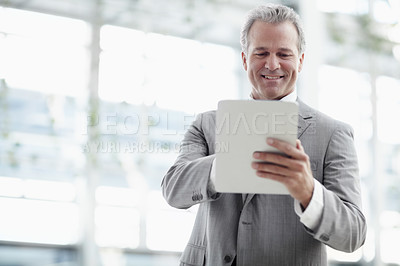 Buy stock photo Mature businessman using a digital tablet while standing in the office