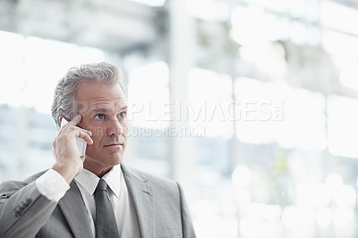 Buy stock photo Mature businessman using a cellphone while standing in the office