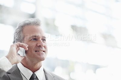 Buy stock photo Mature businessman talking on his cellphone while standing in the office