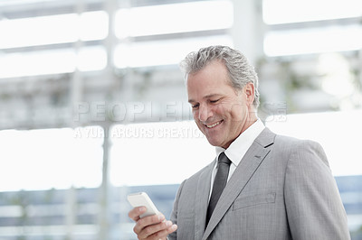 Buy stock photo Mature businessman sending an sms while standing in the office