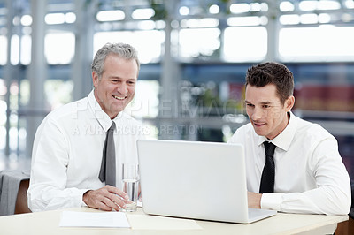 Buy stock photo Two businessmen sitting in front of a laptop