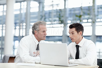 Buy stock photo Two businessmen sitting in front of a notebook