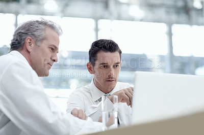 Buy stock photo Two businessmen sharing a laptop in the office