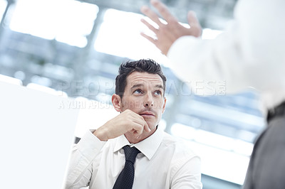 Buy stock photo A businessman sitting down at a notebook and looking up to a colleague as they discuss business