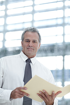 Buy stock photo Portrait of a mature businessman looking at a file in the office