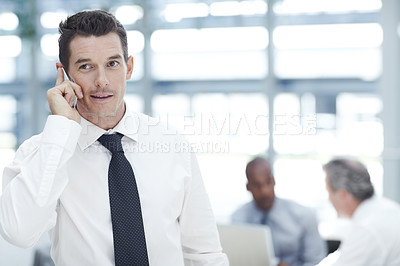 Buy stock photo A young businessman talking on his cellphone in front of two colleagues