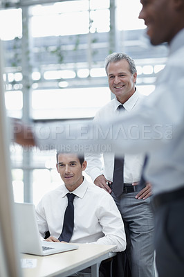 Buy stock photo Businessmen watch and smile as a colleague delivers a presentation on a flipchart