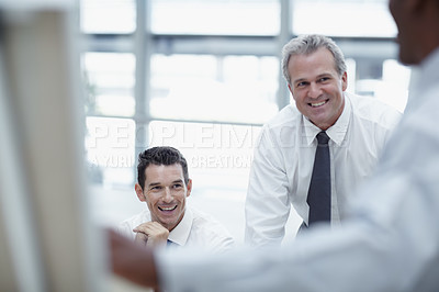 Buy stock photo Businessmen smile and watch as a colleague delivers a presentation on a flipchart