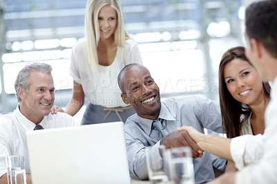 Buy stock photo Shot of a group of business people shaking hands in a meeting