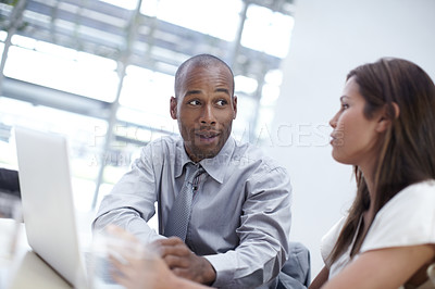 Buy stock photo Two ambitious businesspeople working on a laptop together at the office