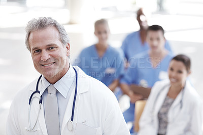 Buy stock photo A doctor standing with colleagues sitting in the background