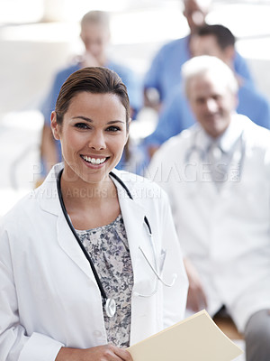 Buy stock photo A doctor standing with colleagues sitting in the background