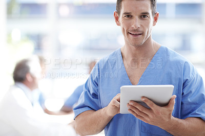 Buy stock photo A medical professional working on a touchpad with colleagues sitting in the background
