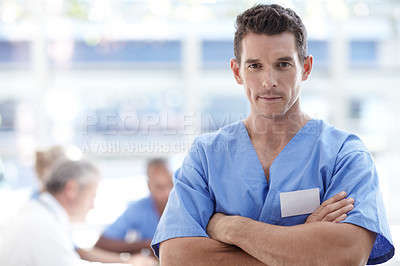 Buy stock photo Medical professional standing with arms crossed and colleagues sitting in the background