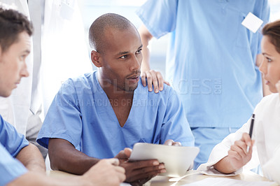 Buy stock photo A doctor and his colleagues have a discussion while gathered at a table