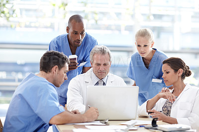 Buy stock photo A team of medical professionals working around a laptop