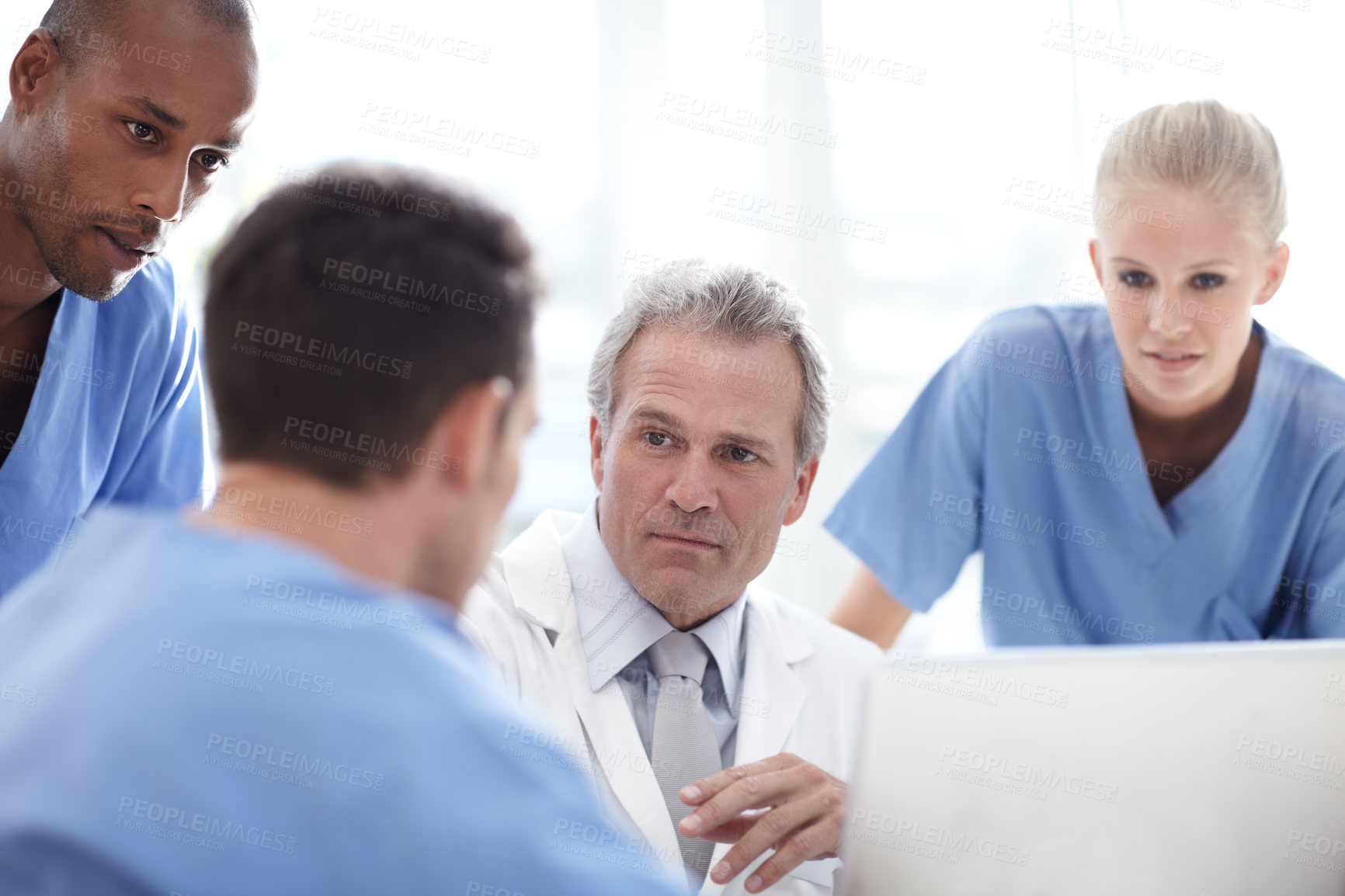 Buy stock photo A senior medical professional in conversation with colleagues