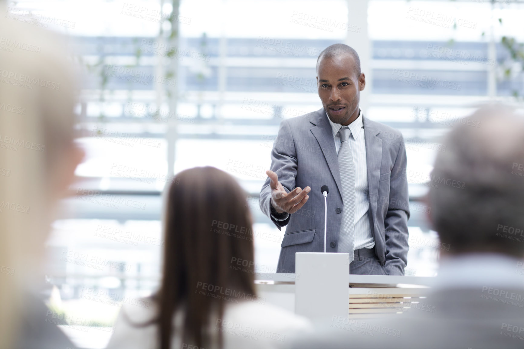 Buy stock photo A handsome young executive seeking his colleagues' input while delivering a speech at a seminar