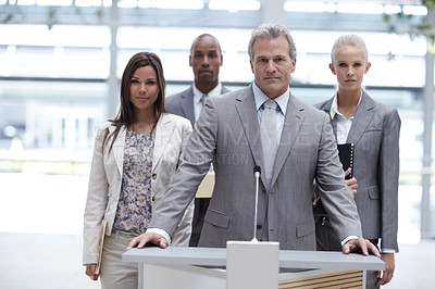 Buy stock photo Portrait of a determined business team standing at a podium together